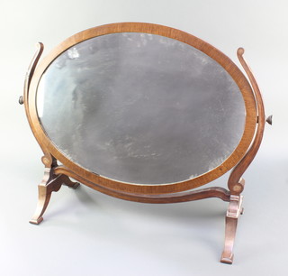 An oval plate dressing table mirror contained in a mahogany swing frame 23"h x 29"w 