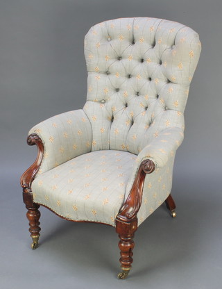 An early Victorian mahogany show frame tub back armchair upholstered in buttoned material, raised on turned turned supports 
