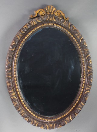 A 19th Century oval plate mirror contained in a decorative carved wooden frame surmounted by a shell cresting rail 31"h x 24"w 
