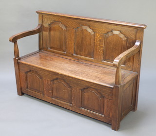 An oak settle with arcaded panelled decoration and hinged lid to the seat, 37 1/2"h x 54"w x 20"d 