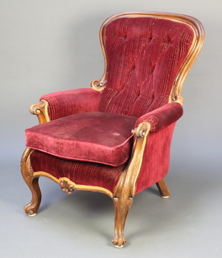 A Victorian mahogany show frame armchair upholstered in red buttoned material raised on carved cabriole supports 