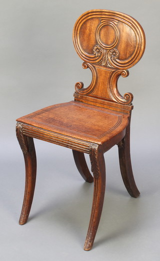 A Regency mahogany hall chair with shaped back and solid seat raised on sabre supports 