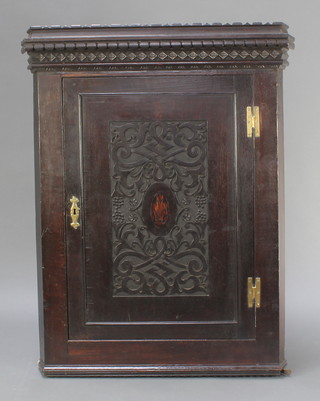 A Victorian carved and ebonised oak hanging corner cabinet fitted shelves enclosed by panelled door and brass H framed hinges 43"h x 32"w x 18"d 