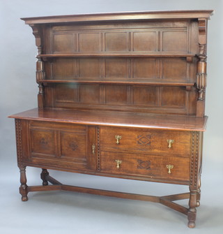 An Edwardian oak dresser, the raised back with moulded cornice fitted 2 shelves with columns to the sides, the base fitted a cupboard enclosed by a panelled door flanked by 2 long drawers with brass pear drop handles, raised on cup and cover supports with Y framed stretcher 73"h x 72"w x 22"d 