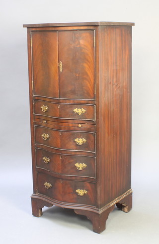 A Georgian style mahogany tall boy/drinks cabinet of serpentine outline, the upper section fitted a cupboard enclosed by panelled door, the base fitted 1 long drawer and brushing slide above 3 long drawers, raised on bracket feet 48"h x 21"w x 17"d 