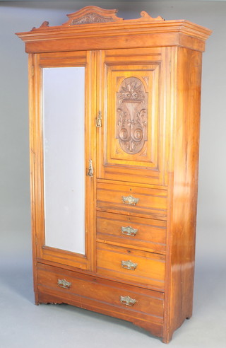 A Victorian carved walnut combination wardrobe, fitted a cupboard enclosed by a bevelled plate mirrored door flanked by a cupboard enclosed by a panelled door above 3 short drawers, the base fitted 1 long drawer 82"h x 48"w 19"d