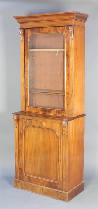 A Victorian mahogany cabinet on cabinet, the upper section with moulded cornice and vitruvian scrolls to the sides, fitted adjustable shelves enclosed by an arched panelled door, raised on a platform base 80"h x 30"w x 15 1/2"d 