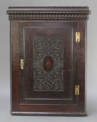 A Victorian carved and ebonised oak hanging corner cabinet fitted shelves enclosed by panelled door and brass H framed hinges 43"h x 32"w x 18"d 