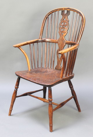 An 18th Century elm Windsor stick and wheel back kitchen chair with solid seat and H framed stretcher, raised on turned supports 
