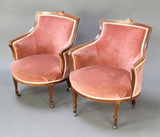A pair of Edwardian inlaid mahogany tub back chairs upholstered in pink material raised on square tapering supports 