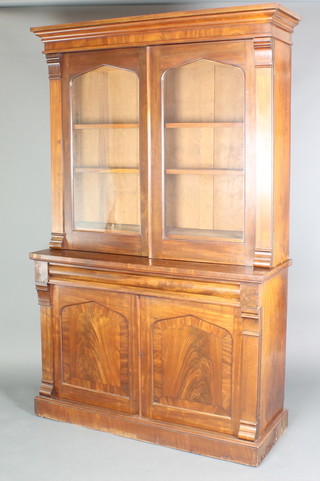 A Victorian mahogany bookcase on cabinet, the upper section with moulded cornice, the shelved interior enclosed by arched glazed panelled doors, the base fitted 1 long drawer above a double cupboard, raised on a platform base 84"h x 51 1/2"w x 18 1/2"d  