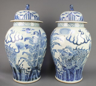 A pair of 18th Century style Chinese blue and white baluster vases and covers decorated with dragons amongst leaves with lion finials 23" 