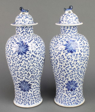 A pair of early 20th Century Chinese blue and white oviform vases decorated with flowers, the lids with shi shi finials 15"
