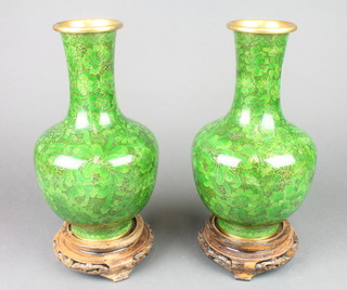 A pair of cloisonne green ground club shaped vases with leaf decoration, raised on hardwood stands 10" (1 has dent to base) 