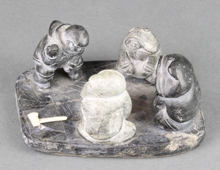 A carved Inuit hardstone figure group of standing figures by a whale head, 2" chips to base