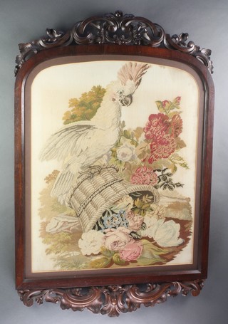 A Victorian Berlin wool work panel of a cockatiel and upturned basket of flowers, contained in a carved rosewood frame 41" x 26", some staining to the central panel 