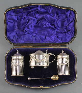 An Edwardian silver 3 piece condiment set with pierced decoration and swags and festoons together with a spoon London 1905, 122 grams, contained in a fitted case 