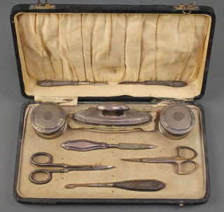 A cased silver mounted manicure set comprising 2 lidded jars, nail buffer, 2 manicure tools and 4 other items