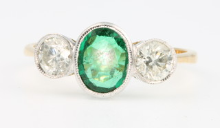 An 18ct yellow gold emerald and diamond ring, the oval cut centre stone approx. 0.75ct flanked by 2 brilliant cut diamonds 0.6ct, size P 1/2 