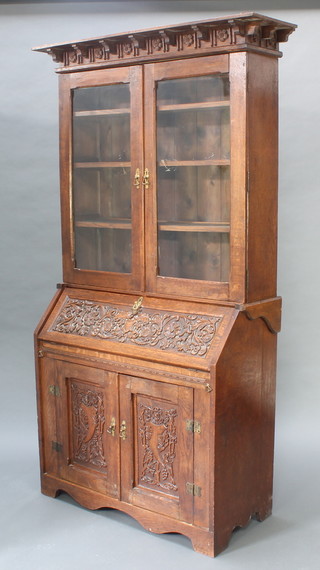 A Victorian carved oak bureau bookcase, the upper section with moulded cornice, the interior fitted adjustable shelves enclosed by a glazed panelled door, the base with fall front revealing pigeon holes and well, above panelled doors, heavily carved throughout 86"h x 41"w x 19"d 