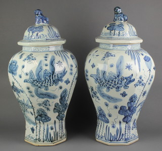A pair of Chinese blue and white 18th Century style octagonal baluster vases and covers decorated with fish and flowers with lion finials 24" 