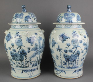 A pair of Chinese blue and white 18th Century style baluster vases and covers with mask handles decorated with fish and motifs, having  lion finials 20" 