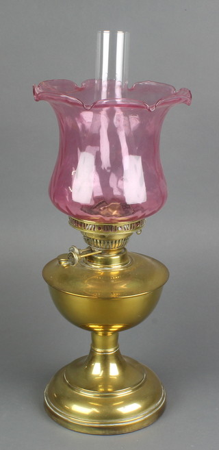 A brass oil lamp with clear glass chimney and purple flared glass shade 