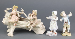 A German figure of a boy with bird 5", a ditto of a girl with doves 5 1/2" and a group of 2 children sitting on a trunk 10" 