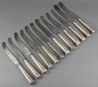A matched set of 12 Georgian dinner knives with silver grips and shell ends 