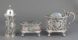 A silver 3 piece condiment with gadroon rims and pierced cut floral and bird decoration comprising mustard and pepper with clear glass liners, a later salt with clear glass liner, London 1838 and 1923, 278 grams 