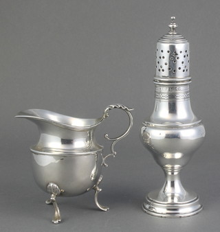 A silver pepper of urn form London 1917 and a silver cream jug with scroll handle marks rubbed, 155 grams 