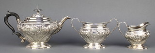 A Victorian repousse silver 3 piece tea set with scroll decoration and ebony mounts, London 1899, 1242 grams 