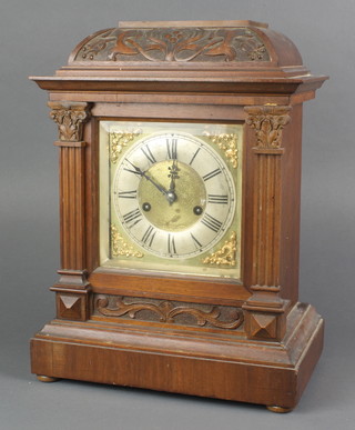 Hamburg American Clock Company, a 14 day striking mantel clock with 8" square dial, silvered chapter ring and Roman numerals contained in a carved walnut case 