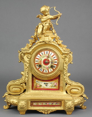A 19th Century French 8 day striking mantel clock with red porcelain dial contained in a gilt painted metal case surmounted by a figure of cupid 
