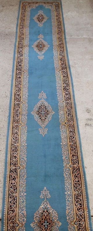 A blue ground Persian Kirman runner with 5 stylised medallions to the centre 136" x 36" 