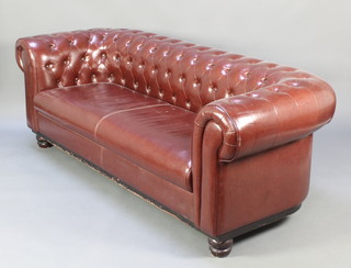 A Chesterfield upholstered in brown buttoned material raised on bun feet