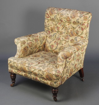 A Victorian Howard style armchair upholstered in tapestry material raised on turned supports 