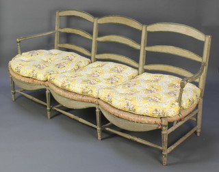 A 19th Century Provincial French painted triple chair back settee with woven rush seat and fitted cushions, raised on turned and fluted supports  