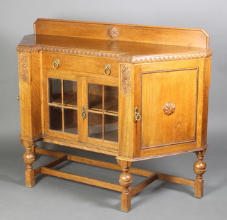 An Art Deco carved light oak sideboard of lozenge form with raised back, the centre fitted a drawer above a cupboard enclosed by lattice work panels flanked by cupboards, raised on cup and cover supports with H framed stretcher 42"h x 54"w x 20"d 