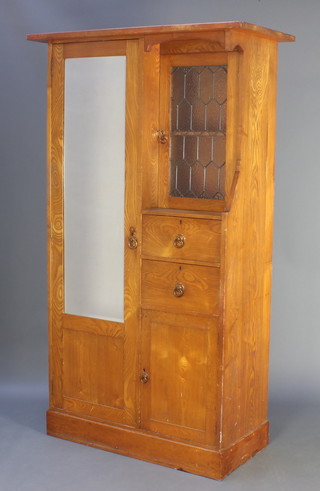 An Art Nouveau light oak combination wardrobe with moulded cornice, having a cupboard enclosed by a bevelled plate mirrored door flanked by a cupboard enclosed by a lead glazed panelled door, fitted 2 long drawers above cupboard 72 1/2"h x 44 1/2"w x 21"d 