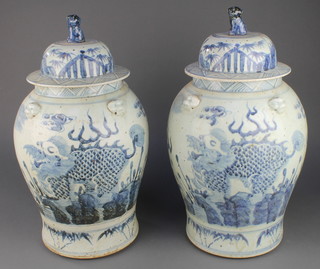 A pair of 18th Century style Chinese blue and white oviform vases and covers decorated with dragons chasing the flaming pearl, having lion finials 18" 