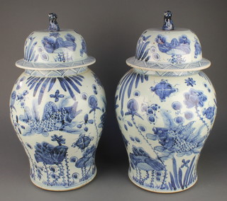 A pair of 18th Century style Chinese blue and white baluster vases and covers decorated with carp amongst seaweed with lion finials 20 1/2" 