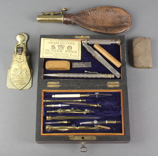 A 19th Century brass and leather shot flask, a brown leather and gilt metal double sovereign case, a Victorian Merry Phipson & Parker paperclip and a geometry set contained in a mahogany case 