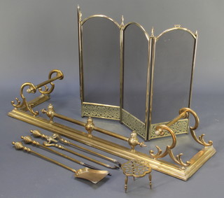 A Victorian style brass fire curb 14" x 52" together with a 3 brass fire side implement set with tongs, poker and shovel, a brass trivet and a brass and mesh 3 fold spark guard