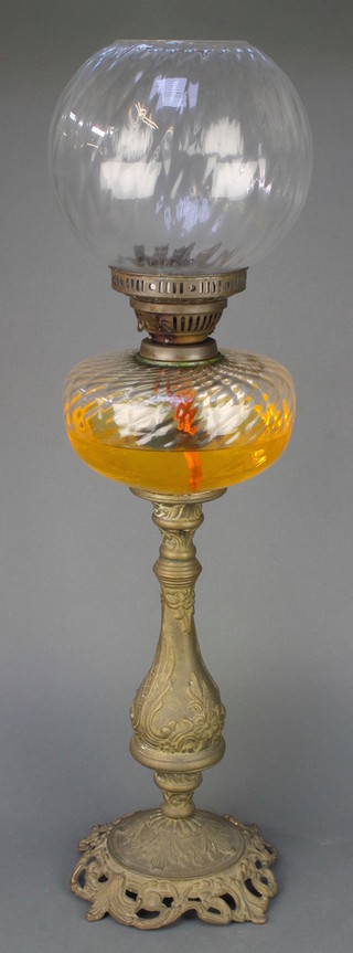 An oil lamp with clear glass reservoir and shade, raised on a gilt metal base 21" 