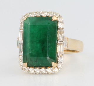An 18ct yellow gold emerald and diamond ring, the rectangular cut stone approx. 8.51ct surrounded by brilliant cut diamonds approx. 0.32ct, size L 1/2