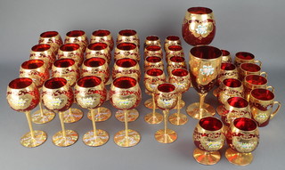 A suite of mid 20th Century Italian red glass and gilt decorated table ware comprising 16 hock glasses, 9 wine glasses, 6 brandies, 4 mugs and 2 vases 