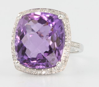 A white gold amethyst and diamond ring, the cushion shaped centre stone approx. 13.6ct surrounded by brilliant cut diamonds approx. 0.4ct, size N