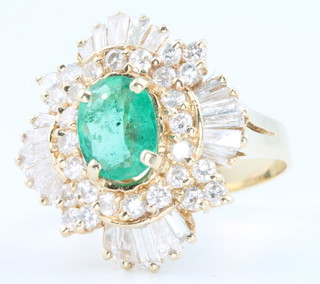 A 14ct yellow gold emerald and diamond ring the oval centre stone surrounded by tapered baguette and brilliant cut diamonds, size M 