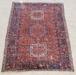 A blue and red ground Persian Heriz rug with stylised diamond to the centre supported by 2 square medallions, in wear 76" x 58" 